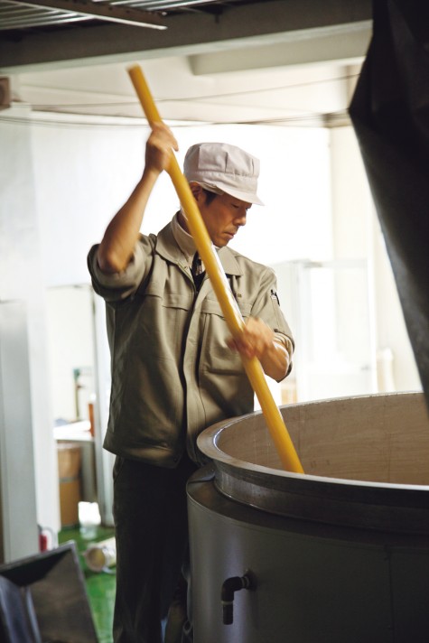 The mash is stirred with a wooden stick.